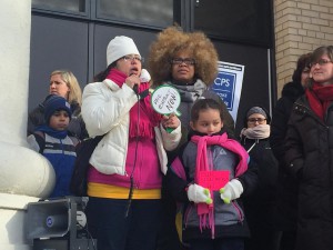 Teachers, parents and children stand in front of Saucedo Scholastic Academy as they rally against budget cuts