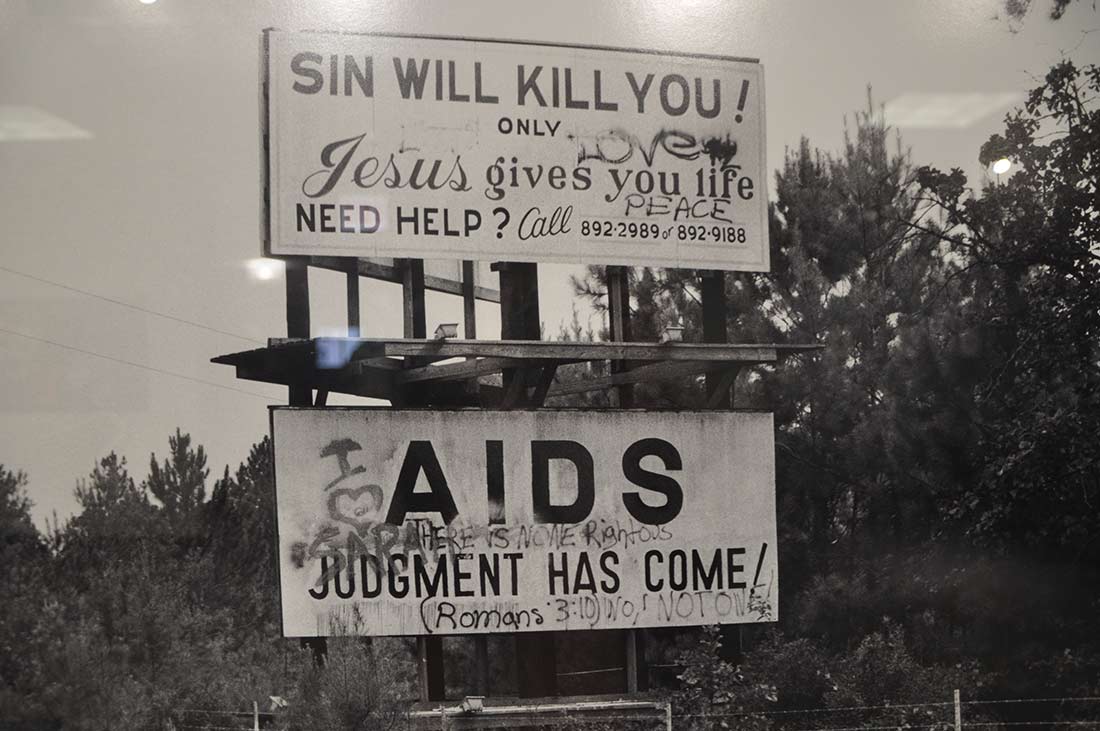 A photograph of two billboards says AIDS judgement has come for gays and graffiti talking back to homophobia.