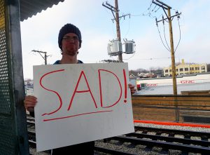 Man holds his sign at the Berwyn stop