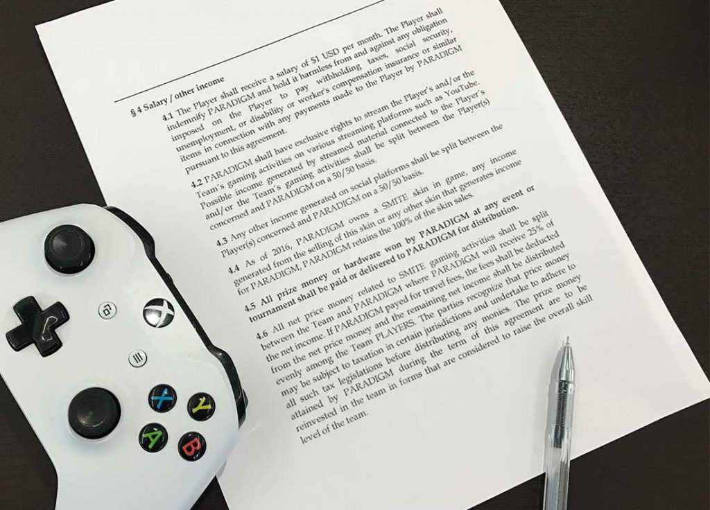 Photo of a pen, an Xbox One controller and a copy of an e-sports player contract.